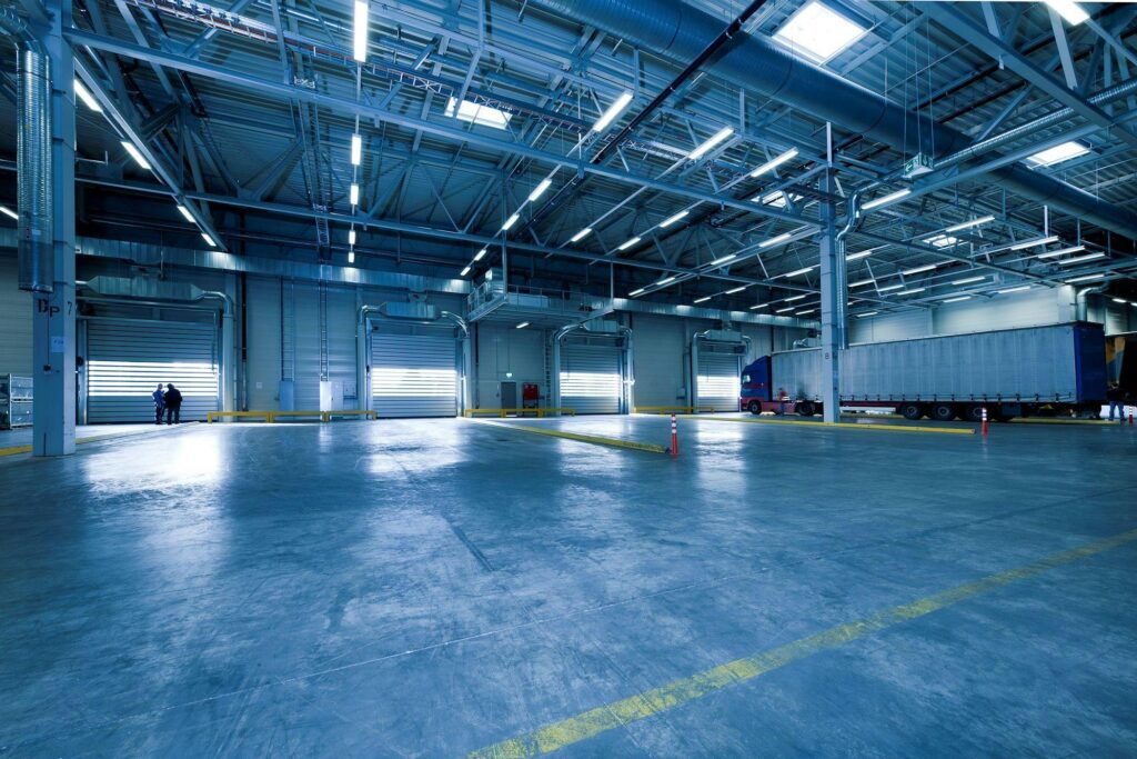 pexels-photo-221047-221047 Large warehouse interior with docked truck, ideal for logistics and warehousing.